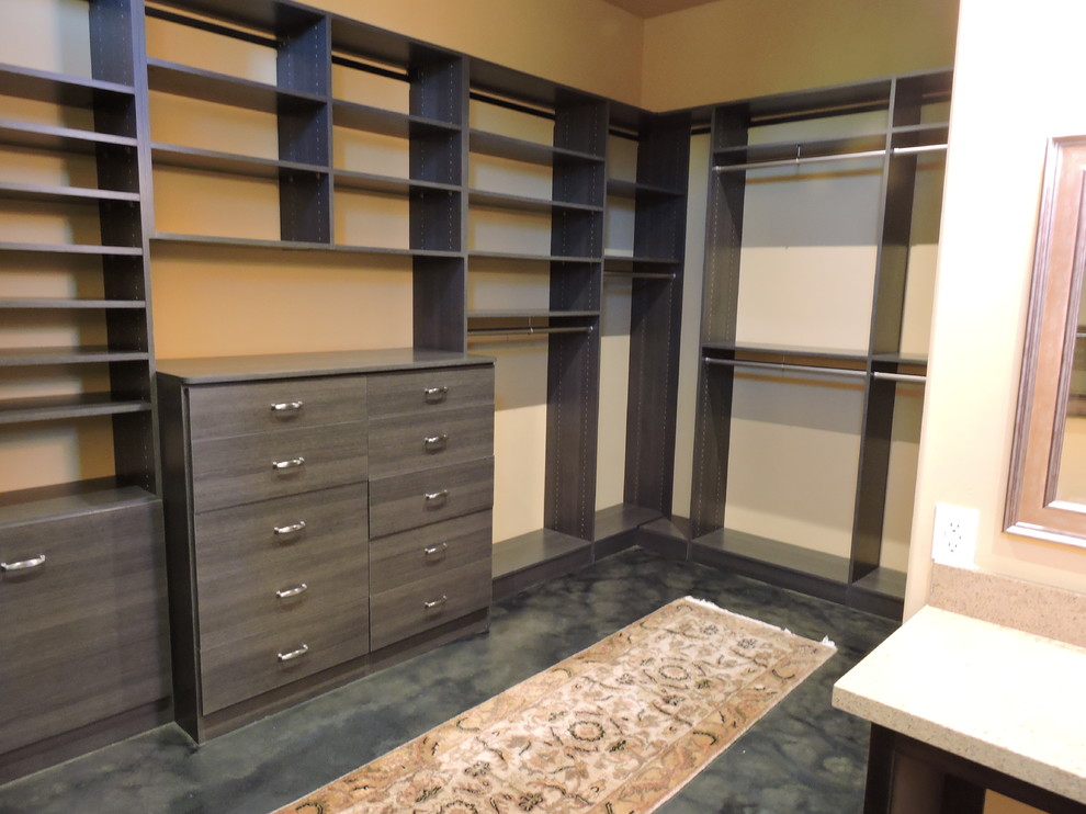 Photo of a large contemporary walk-in wardrobe in Sacramento with flat-panel cabinets, dark wood cabinets, concrete floors and grey floor.