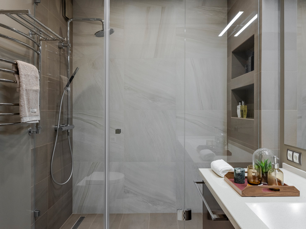 Exempel på ett litet modernt beige beige badrum med dusch, med släta luckor, bruna skåp, en öppen dusch, en vägghängd toalettstol, brun kakel, porslinskakel, bruna väggar, klinkergolv i porslin, ett integrerad handfat, bänkskiva i akrylsten, brunt golv och dusch med gångjärnsdörr