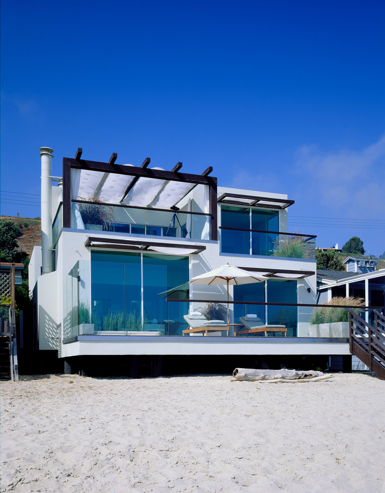 Photo of a mid-sized beach style two-storey glass exterior in Los Angeles with a flat roof.