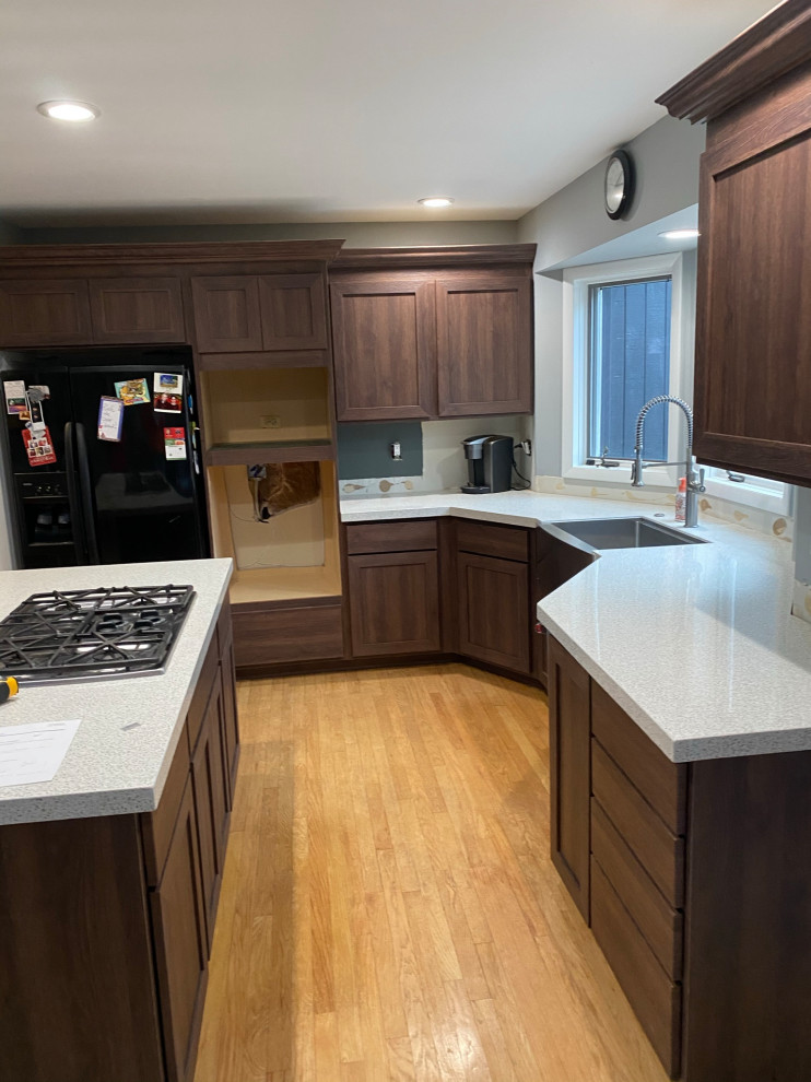 Foto di una cucina moderna di medie dimensioni con lavello sottopiano, ante in stile shaker, ante in legno bruno, top in granito, elettrodomestici neri, parquet chiaro, pavimento arancione e top grigio