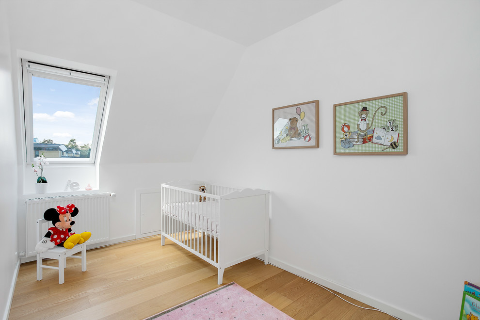 Photo of a mid-sized scandinavian gender-neutral nursery in Other with white walls, light hardwood floors and beige floor.