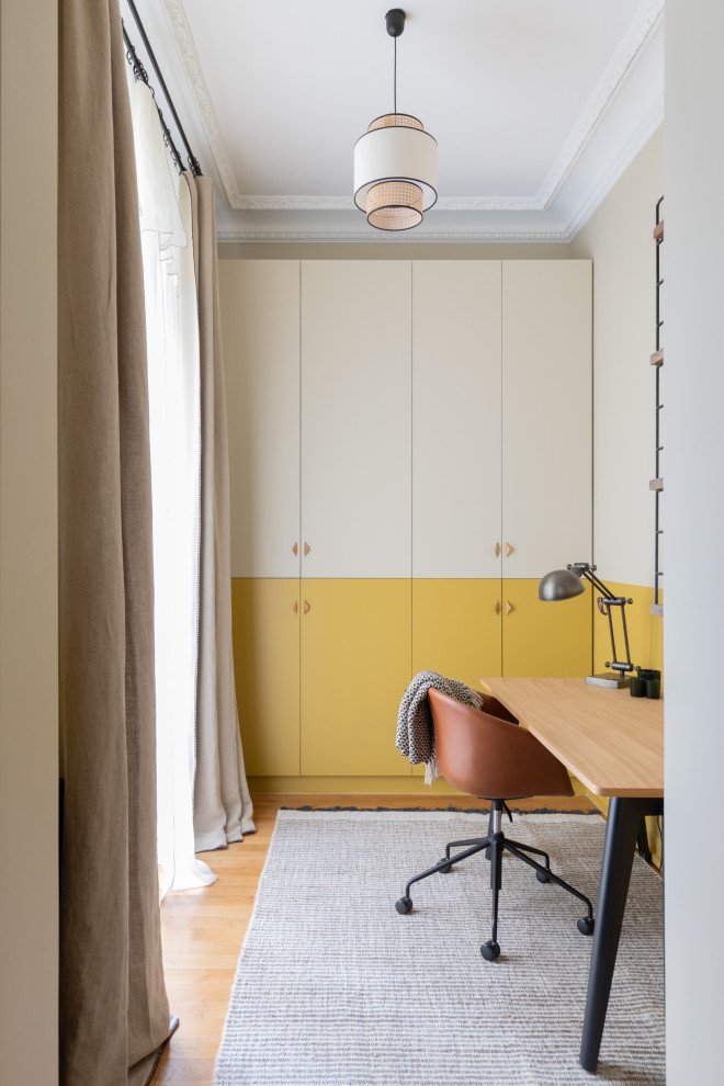 На фото: кабинет в современном стиле с желтыми стенами, паркетным полом среднего тона, отдельно стоящим рабочим столом и коричневым полом
