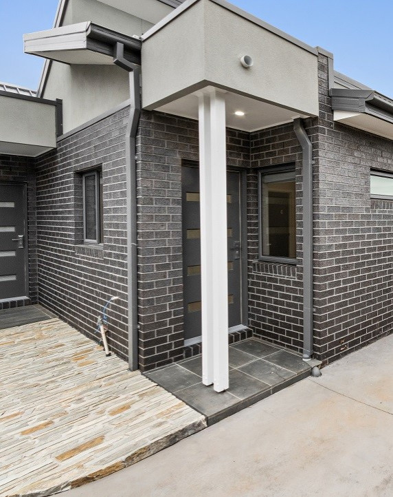 Photo of a small industrial front door in Melbourne with metallic walls, granite floors, a single front door, a gray front door, grey floor, vaulted and brick walls.