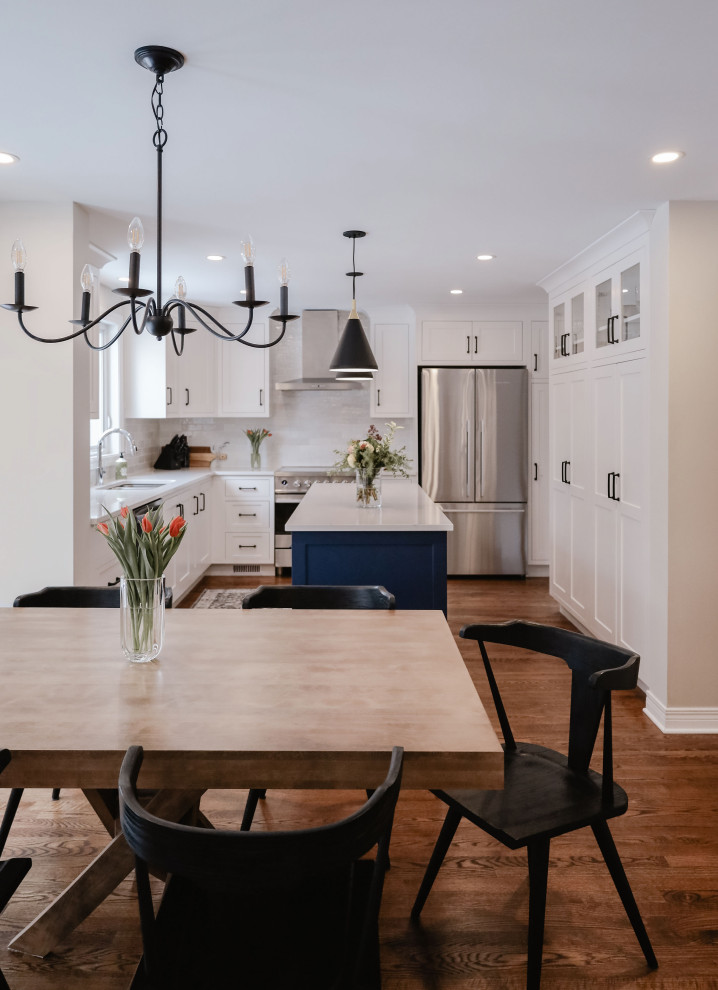 Example of a small transitional u-shaped medium tone wood floor and brown floor eat-in kitchen design in Ottawa with an undermount sink, shaker cabinets, white cabinets, quartz countertops, white backsplash, subway tile backsplash, stainless steel appliances, an island and white countertops
