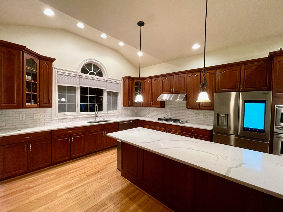 Photo of a large transitional l-shaped eat-in kitchen in DC Metro with an undermount sink, white splashback, ceramic splashback, stainless steel appliances and with island.
