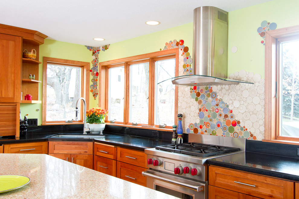 Photo of an expansive eclectic u-shaped eat-in kitchen in Minneapolis with an undermount sink, recessed-panel cabinets, medium wood cabinets, multi-coloured splashback, mosaic tile splashback, stainless steel appliances, medium hardwood floors and with island.