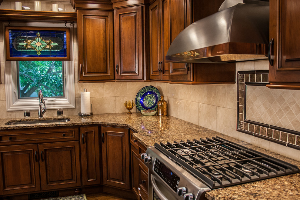 This is an example of a mid-sized traditional l-shaped open plan kitchen in Other with an undermount sink, raised-panel cabinets, medium wood cabinets, granite benchtops, stainless steel appliances, medium hardwood floors and with island.