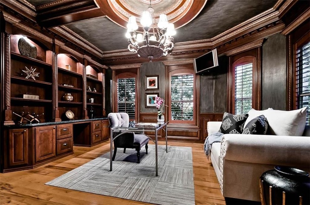 Photo of an expansive transitional home office in Other with black walls, medium hardwood floors, a freestanding desk and brown floor.
