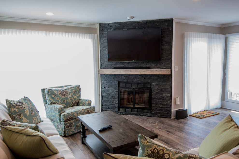 This is an example of a mid-sized contemporary open concept family room in Other with beige walls, vinyl floors, a standard fireplace, a stone fireplace surround and a wall-mounted tv.