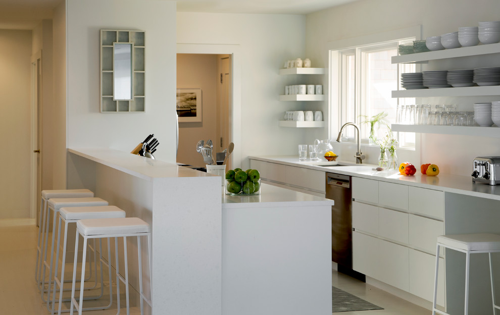 Design ideas for a beach style galley kitchen in Boston with an undermount sink, flat-panel cabinets, white cabinets, stainless steel appliances and a peninsula.