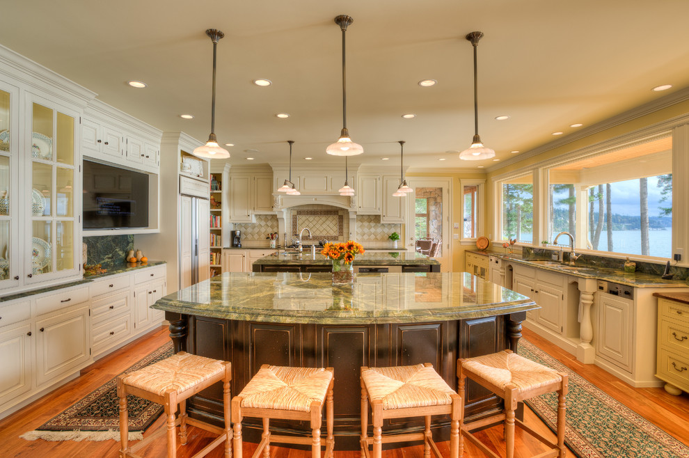 This is an example of a traditional u-shaped kitchen in Seattle with an undermount sink, raised-panel cabinets, white cabinets, panelled appliances, medium hardwood floors, multiple islands, brown floor and green benchtop.