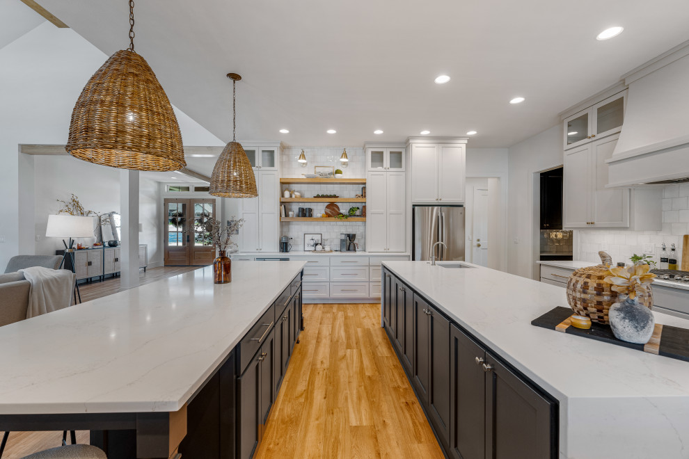Kitchen - mid-sized transitional u-shaped light wood floor kitchen idea in Dallas with a farmhouse sink, shaker cabinets, gray cabinets, quartz countertops, white backsplash, porcelain backsplash, stainless steel appliances, two islands and white countertops