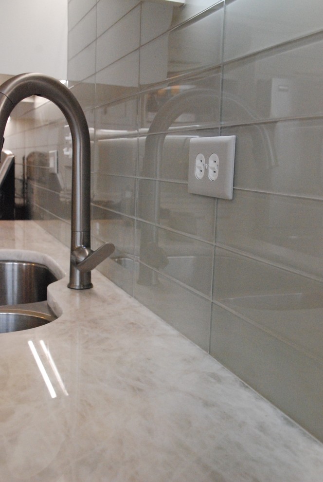 Transitional l-shaped light wood floor eat-in kitchen photo in Chicago with a double-bowl sink, recessed-panel cabinets, white cabinets, quartzite countertops, gray backsplash, glass tile backsplash, stainless steel appliances and an island