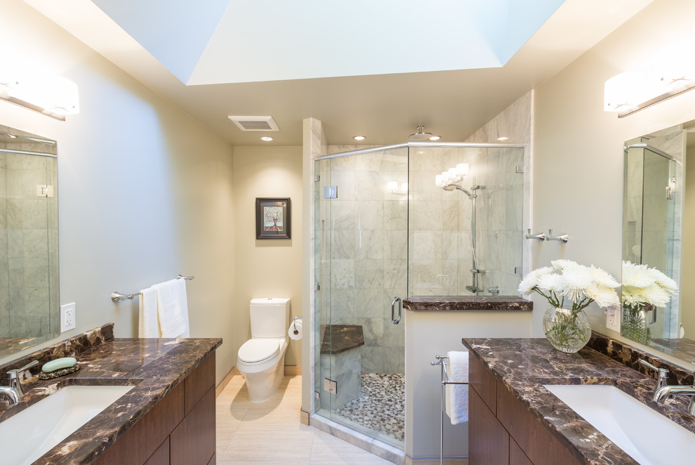 Photo of a mid-sized contemporary master bathroom in Vancouver with an undermount sink, flat-panel cabinets, medium wood cabinets, marble benchtops, a corner shower, a two-piece toilet, stone tile, porcelain floors, beige walls and beige tile.