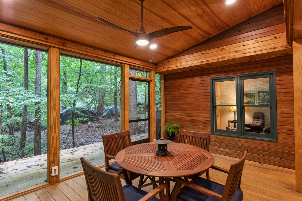 This is an example of a large rustic screened-in back porch design in Raleigh with decking and a roof extension.