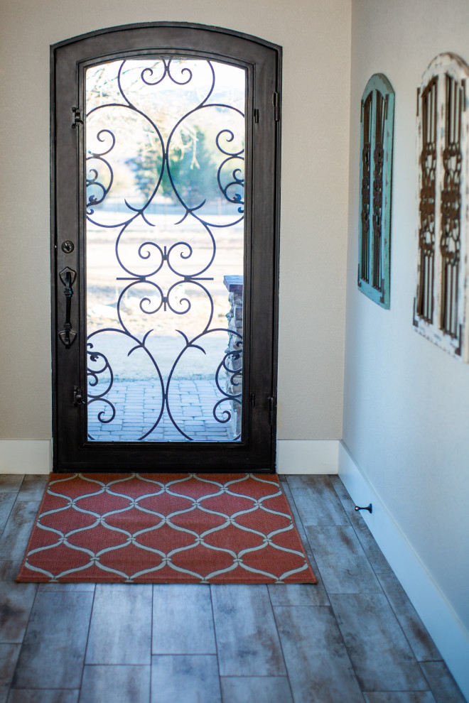 This is an example of a large country foyer in Phoenix with beige walls, porcelain floors, a single front door, a brown front door and beige floor.