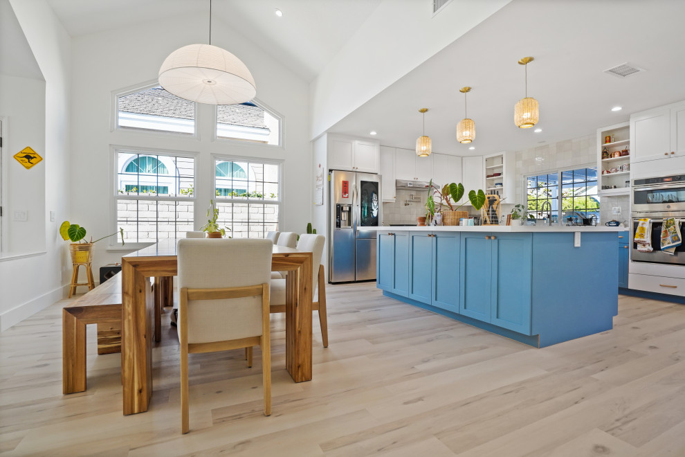 Cette photo montre une salle à manger ouverte sur la cuisine rétro de taille moyenne avec un mur blanc, un sol en vinyl, un sol beige et un plafond voûté.
