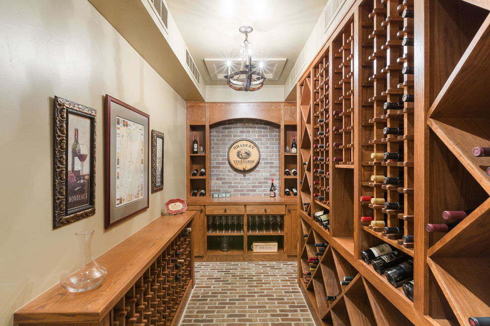 This is an example of a traditional wine cellar in Denver with brick floors and storage racks.
