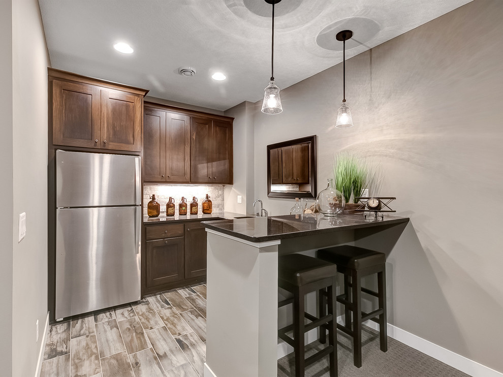 Design ideas for a mid-sized transitional galley seated home bar in Minneapolis with an undermount sink, shaker cabinets, dark wood cabinets, granite benchtops, grey splashback, stone tile splashback, porcelain floors and brown floor.