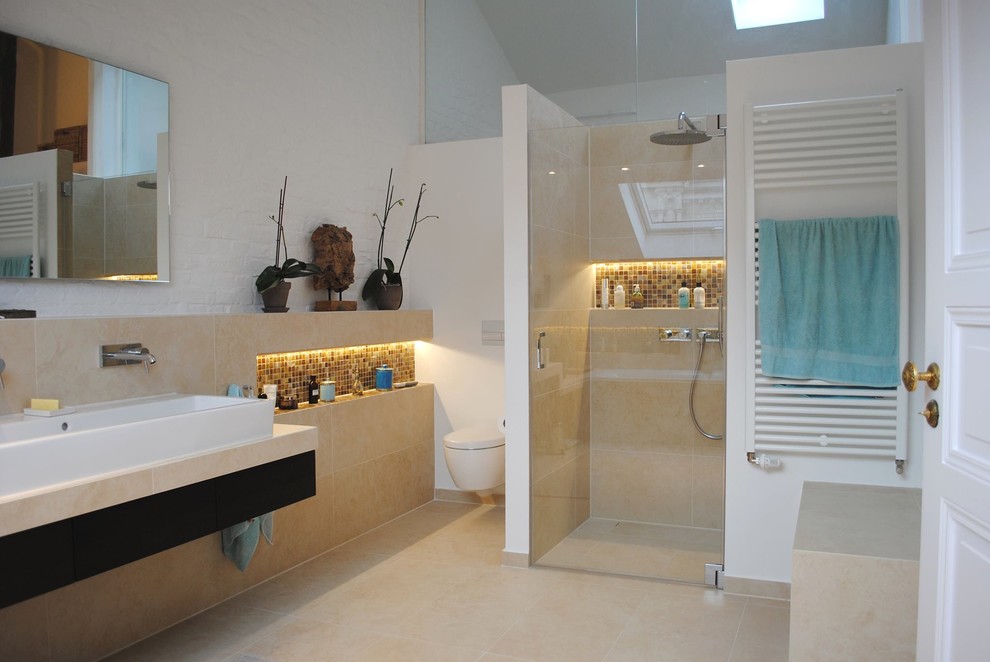 Badezimmer With Duschnische, Wandtoilette, beigen Fliesen, Steinfliesen, weißer Wandfarbe, Kalkstein, Aufsatzwaschbecken, flächenbündigen Schrankfronten, dunklen Holzschränken, beigem Boden and Falttür-Duschabtrennung in Berlin
