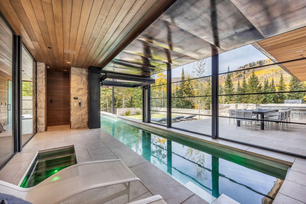 Foto di un'ampia piscina coperta monocorsia minimalista rettangolare con pavimentazioni in pietra naturale