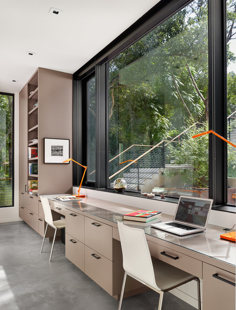 This is an example of a contemporary home office in Austin with white walls, a built-in desk and grey floor.