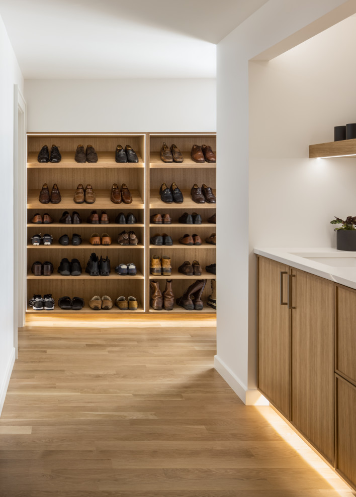 Inspiration for a small contemporary storage and wardrobe in Kansas City with flat-panel cabinets, brown cabinets, light hardwood floors and brown floor.