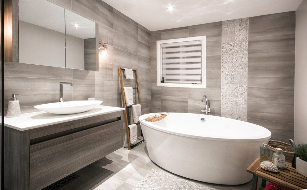 This is an example of a large traditional master bathroom in Montreal with flat-panel cabinets, brown cabinets, a freestanding tub, an alcove shower, a one-piece toilet, beige tile, ceramic tile, beige walls, ceramic floors, a vessel sink, engineered quartz benchtops, beige floor, a sliding shower screen and white benchtops.
