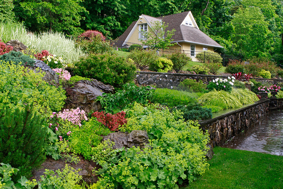 Design ideas for a large victorian full sun backyard concrete paver retaining wall landscape in New York.