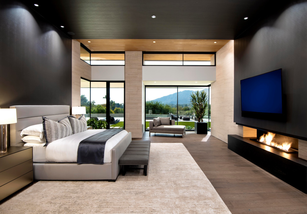 This is an example of an expansive contemporary master bedroom in Phoenix with black walls, dark hardwood floors, a ribbon fireplace, wallpaper and wallpaper.
