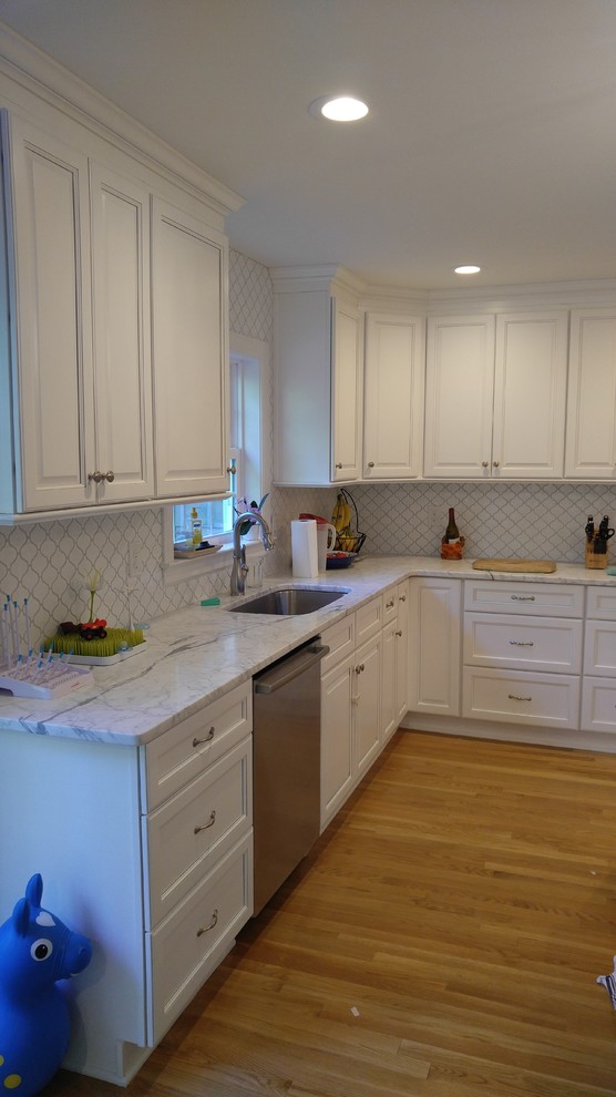 This is an example of a mid-sized transitional kitchen in Richmond with an undermount sink, recessed-panel cabinets, white cabinets, marble benchtops, white splashback, stainless steel appliances and light hardwood floors.