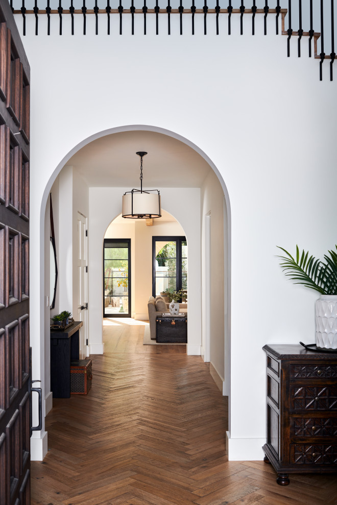 Photo of a small mediterranean entry hall in Los Angeles with white walls, medium hardwood floors, a single front door, a brown front door and beige floor.