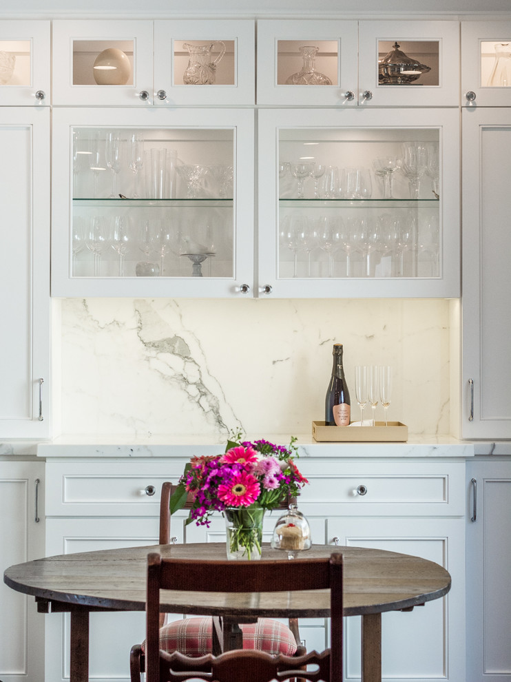 Photo of a mid-sized traditional single-wall wet bar in Los Angeles with recessed-panel cabinets, white cabinets, white splashback, no sink, marble benchtops, stone slab splashback and grey benchtop.