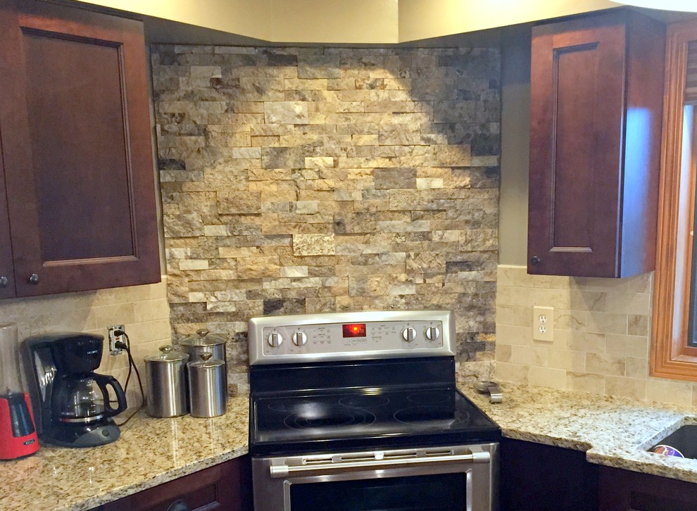 Example of a mid-sized classic kitchen design with an undermount sink, recessed-panel cabinets, dark wood cabinets, granite countertops, beige backsplash, porcelain backsplash, stainless steel appliances and multicolored countertops