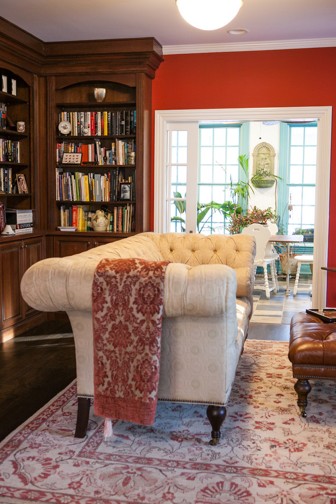 This is an example of a traditional enclosed living room in New York with red walls and dark hardwood floors.