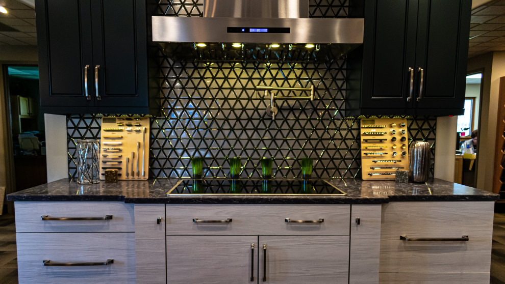 Small transitional single-wall vinyl floor and gray floor open concept kitchen photo with flat-panel cabinets, gray cabinets, quartz countertops, metallic backsplash, glass tile backsplash, black appliances, an island and gray countertops
