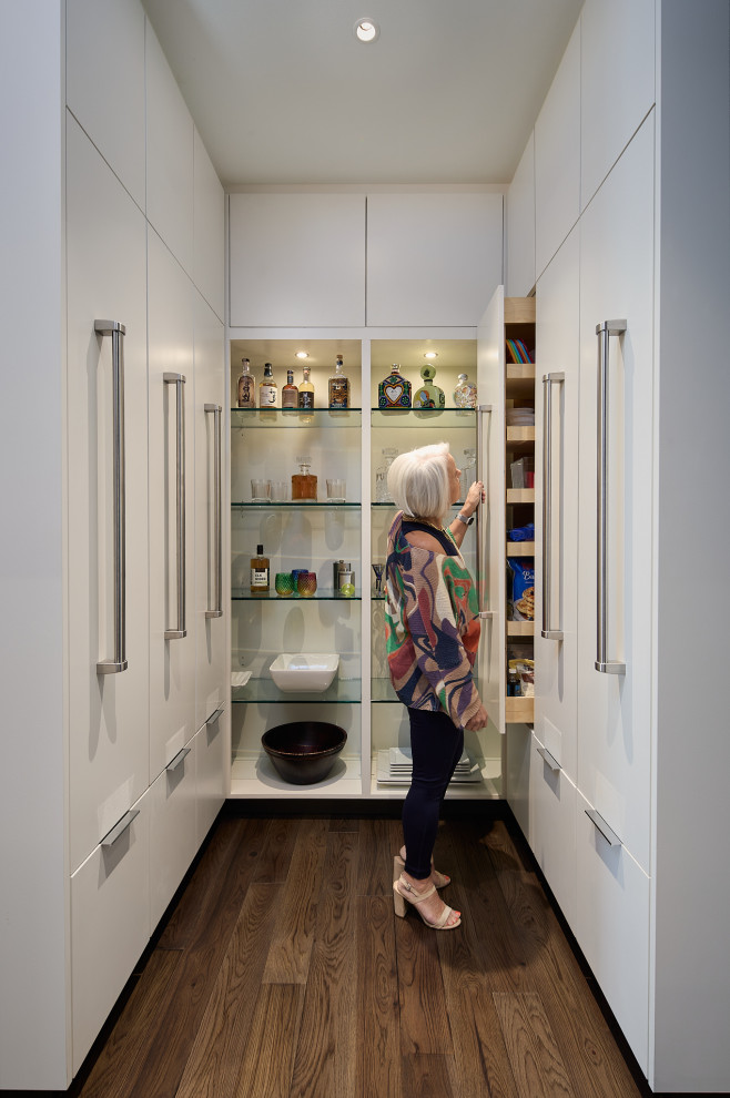 This is an example of a mid-sized modern galley kitchen pantry in Seattle with flat-panel cabinets, white cabinets, dark hardwood floors, brown floor and white benchtop.