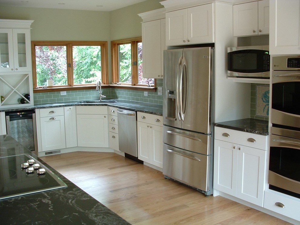Example of a mid-sized transitional l-shaped light wood floor and brown floor eat-in kitchen design in Baltimore with an undermount sink, shaker cabinets, white cabinets, granite countertops, green backsplash, porcelain backsplash, stainless steel appliances and an island