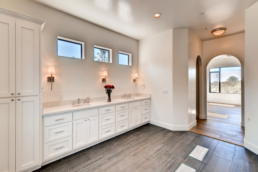 Large traditional master bathroom in Sacramento with shaker cabinets, white cabinets, a freestanding tub, an alcove shower, beige walls, dark hardwood floors, an undermount sink, marble benchtops, brown floor, a hinged shower door and grey benchtops.