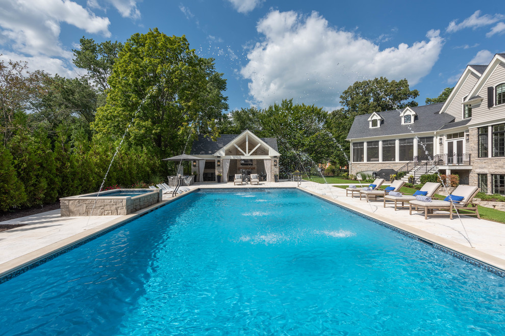 Expansive traditional backyard rectangular pool in Chicago with a pool house and natural stone pavers.