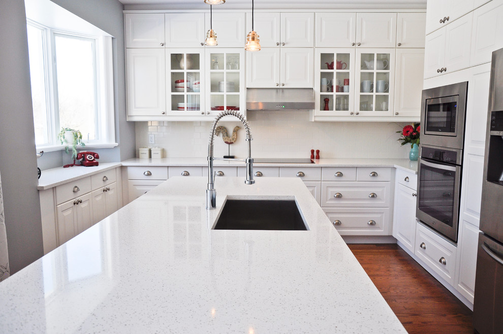 Transitional eat-in kitchen photo in Ottawa with an undermount sink, raised-panel cabinets, white cabinets, quartz countertops, white backsplash, porcelain backsplash, stainless steel appliances and an island