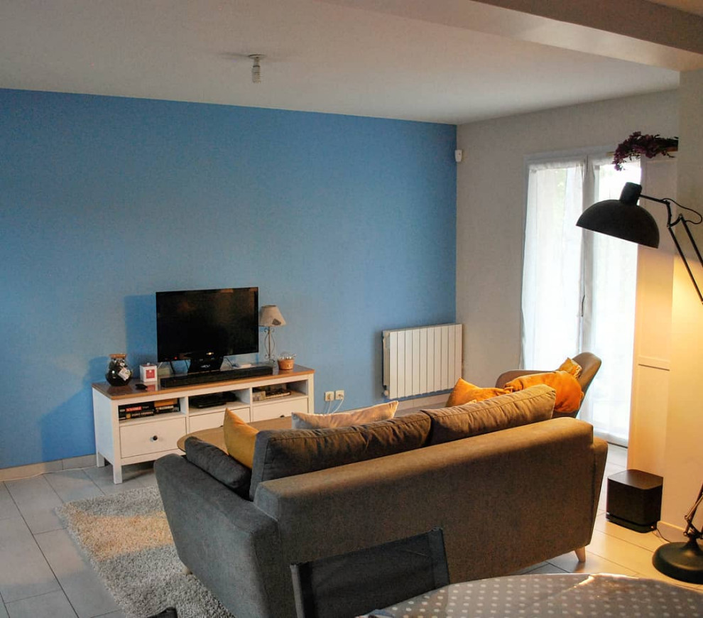 На фото: открытая гостиная комната среднего размера:: освещение в стиле фьюжн с синими стенами, полом из керамической плитки, печью-буржуйкой, фасадом камина из каменной кладки, отдельно стоящим телевизором и белым полом с