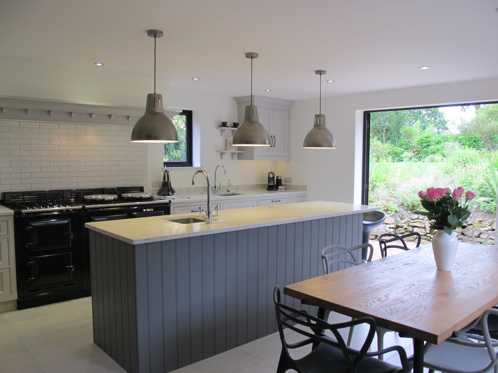Photo of a large contemporary u-shaped eat-in kitchen in Surrey with a single-bowl sink, recessed-panel cabinets, grey cabinets, solid surface benchtops, white splashback, subway tile splashback, stainless steel appliances, porcelain floors and with island.