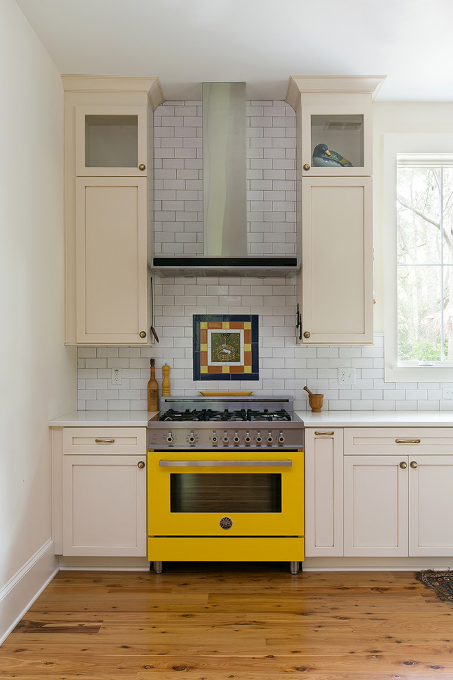 Inspiration for a mid-sized traditional single-wall eat-in kitchen in Charleston with an undermount sink, shaker cabinets, white cabinets, white splashback, subway tile splashback, coloured appliances, medium hardwood floors and with island.