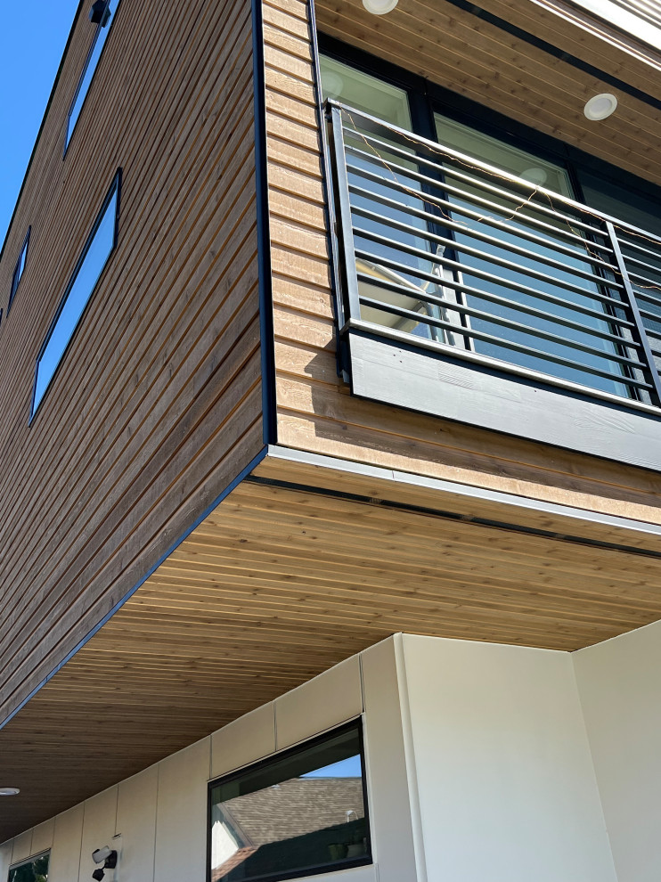 This is an example of a large modern three-storey white duplex exterior in Seattle with concrete fiberboard siding, a flat roof, a metal roof, a black roof and board and batten siding.