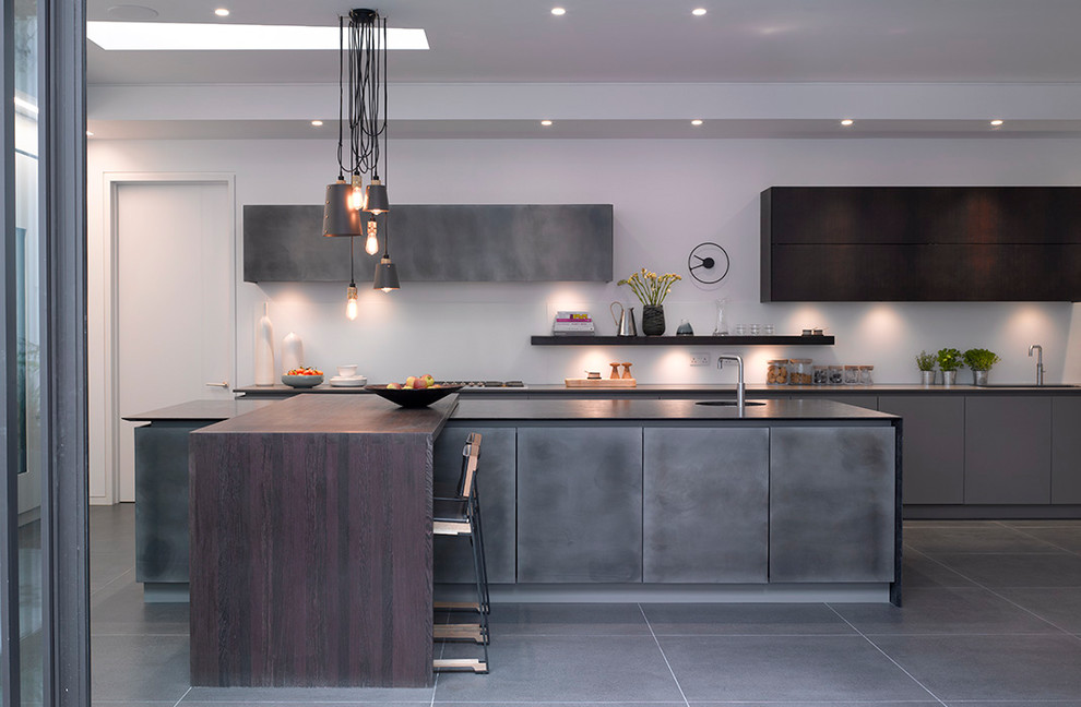 Photo of a large contemporary single-wall open plan kitchen in London with flat-panel cabinets, grey cabinets, quartzite benchtops, white splashback, glass sheet splashback, panelled appliances, ceramic floors, with island, grey floor and grey benchtop.