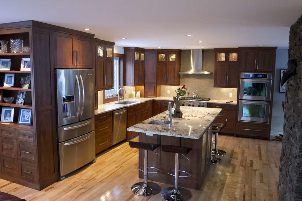 Example of a mid-sized transitional l-shaped light wood floor and beige floor open concept kitchen design with an undermount sink, shaker cabinets, dark wood cabinets, quartz countertops, beige backsplash, porcelain backsplash, stainless steel appliances and an island