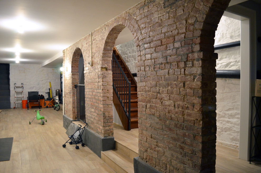 Photo of a large traditional basement in New York with white walls, light hardwood floors, no fireplace and brown floor.