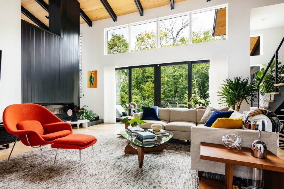 Inspiration for a large midcentury open concept living room in Nashville with white walls, light hardwood floors, a two-sided fireplace, a metal fireplace surround, a wall-mounted tv and brown floor.