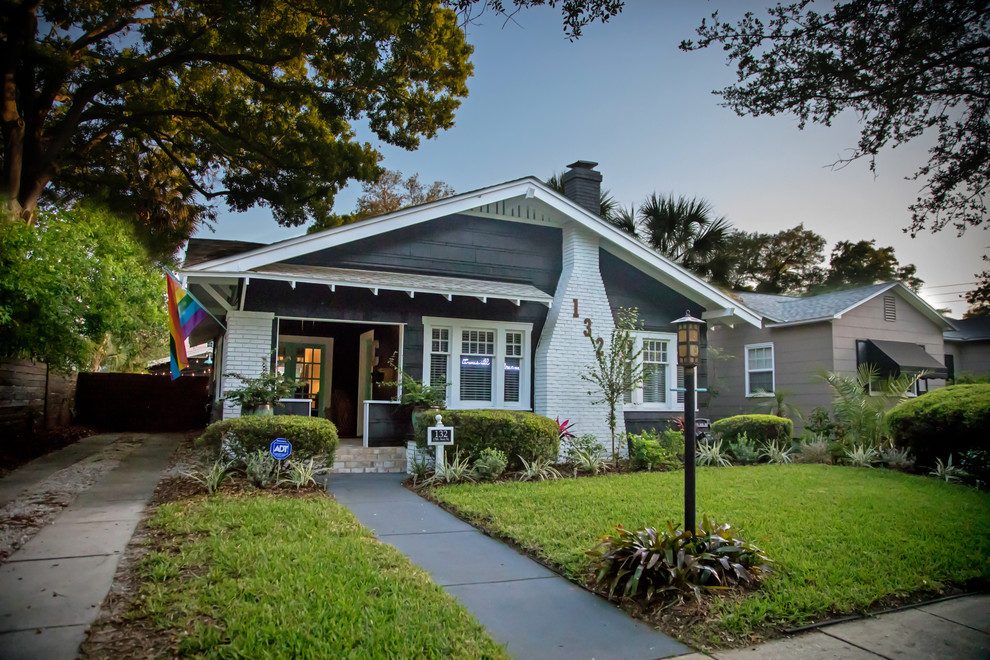 Photo of a large arts and crafts one-storey black house exterior in Tampa with wood siding, a gable roof and a shingle roof.